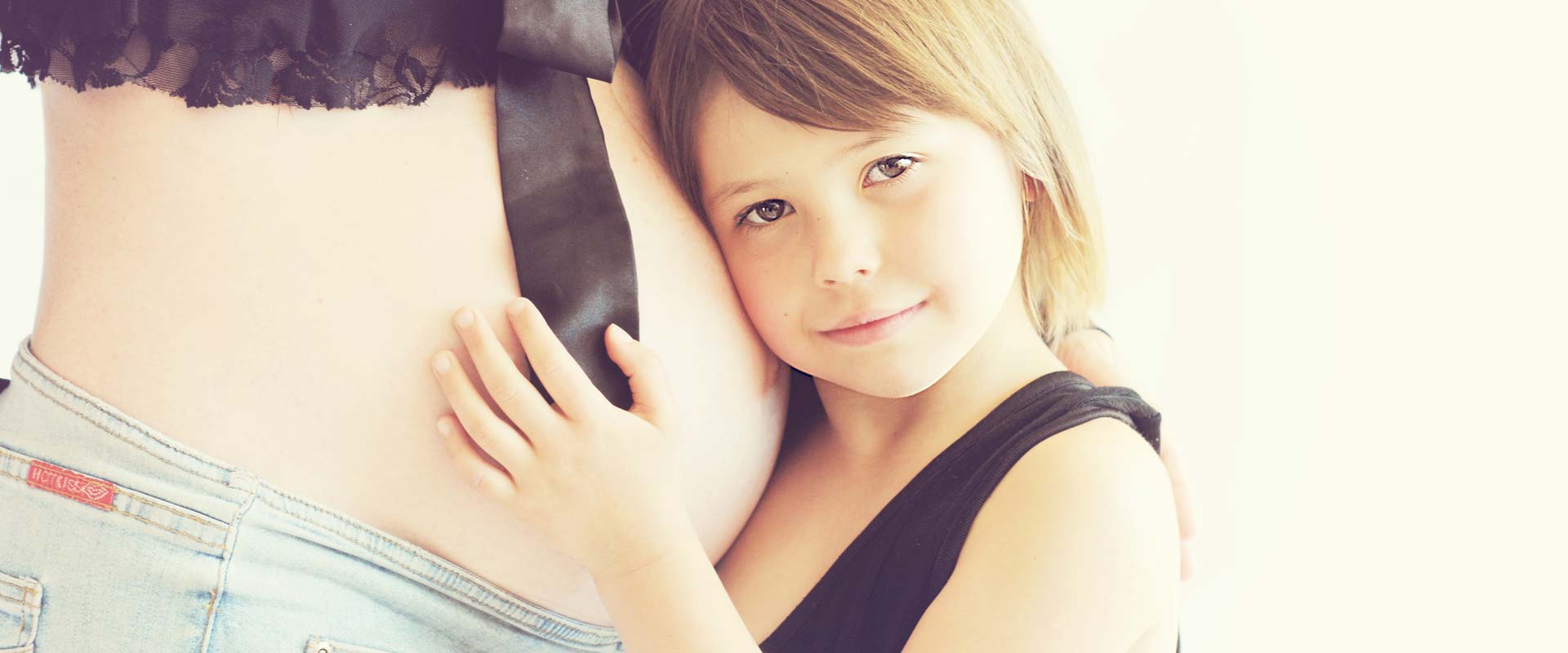 a small child resting their head on the pregnant mothers belly