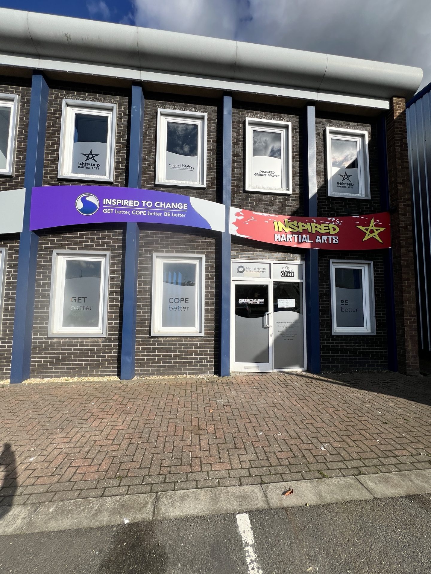 Front entrance of Inspired To Change at Aston Business Park, Peterborough, with the purple sign reading GET better, COPE better, BE better.