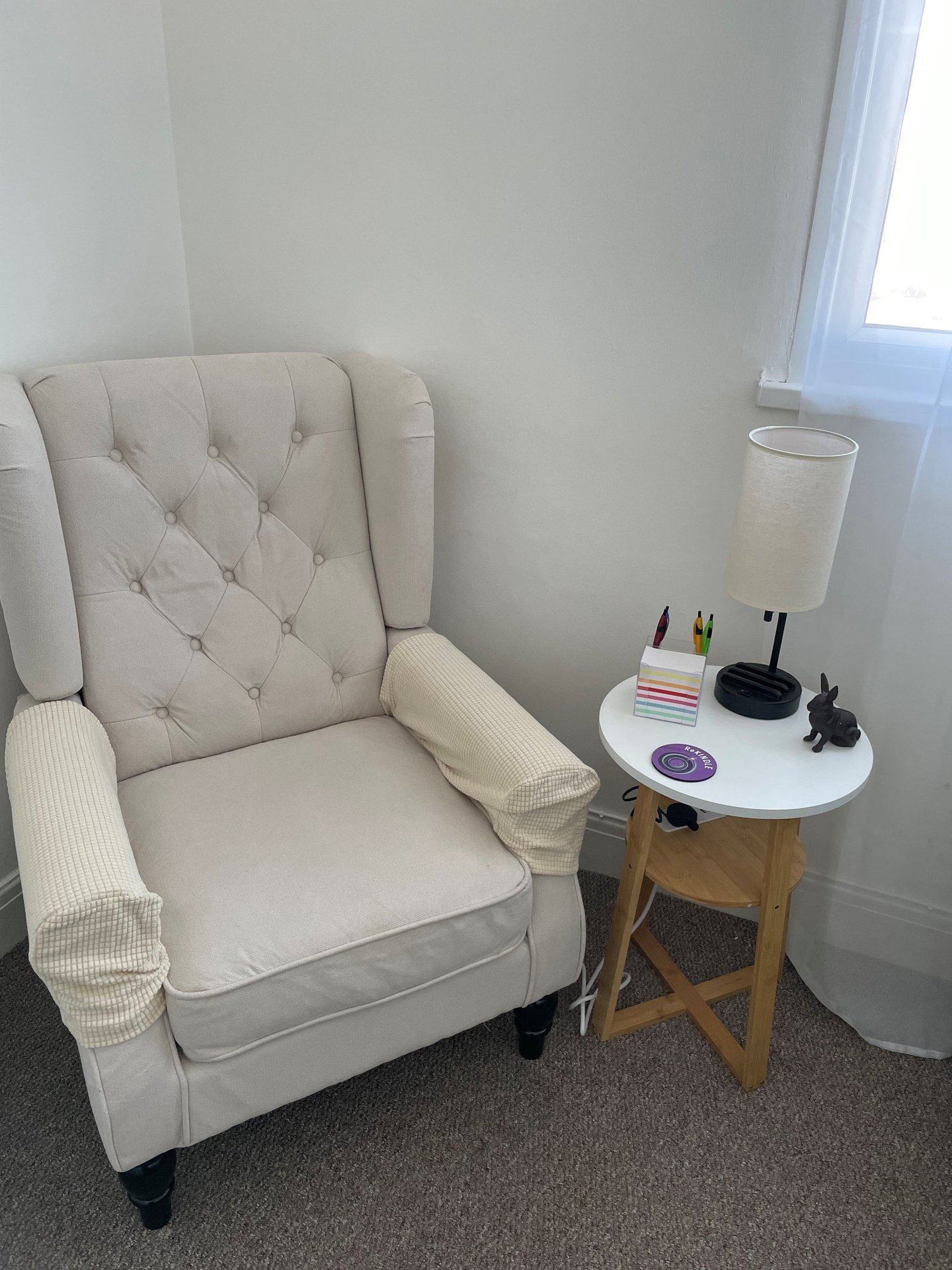 Comfortable cream client chair and side table in Keeley Smith’s hypnotherapy room in Southend-on-Sea.