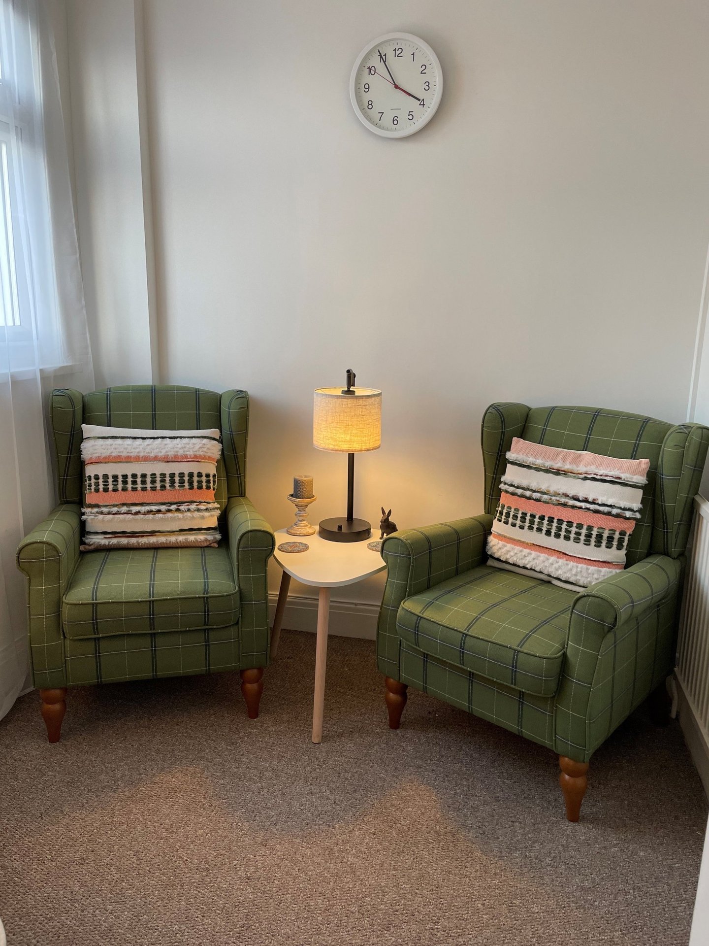 Two green checked armchairs either side of a lamp in Keeley Smith’s hypnotherapy room in Southend-on-Sea.