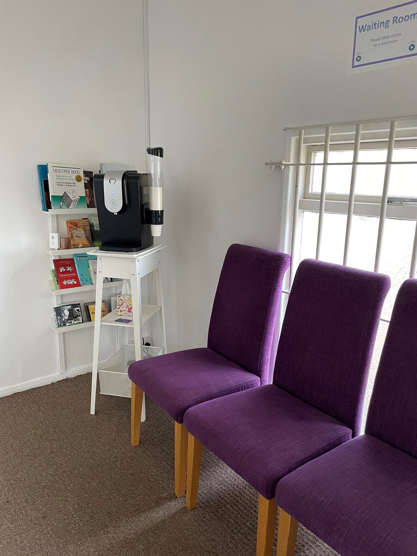 Waiting room with purple chairs, a water dispenser and a bookshelf at Keeley Smith’s practice in Southend-on-Sea.