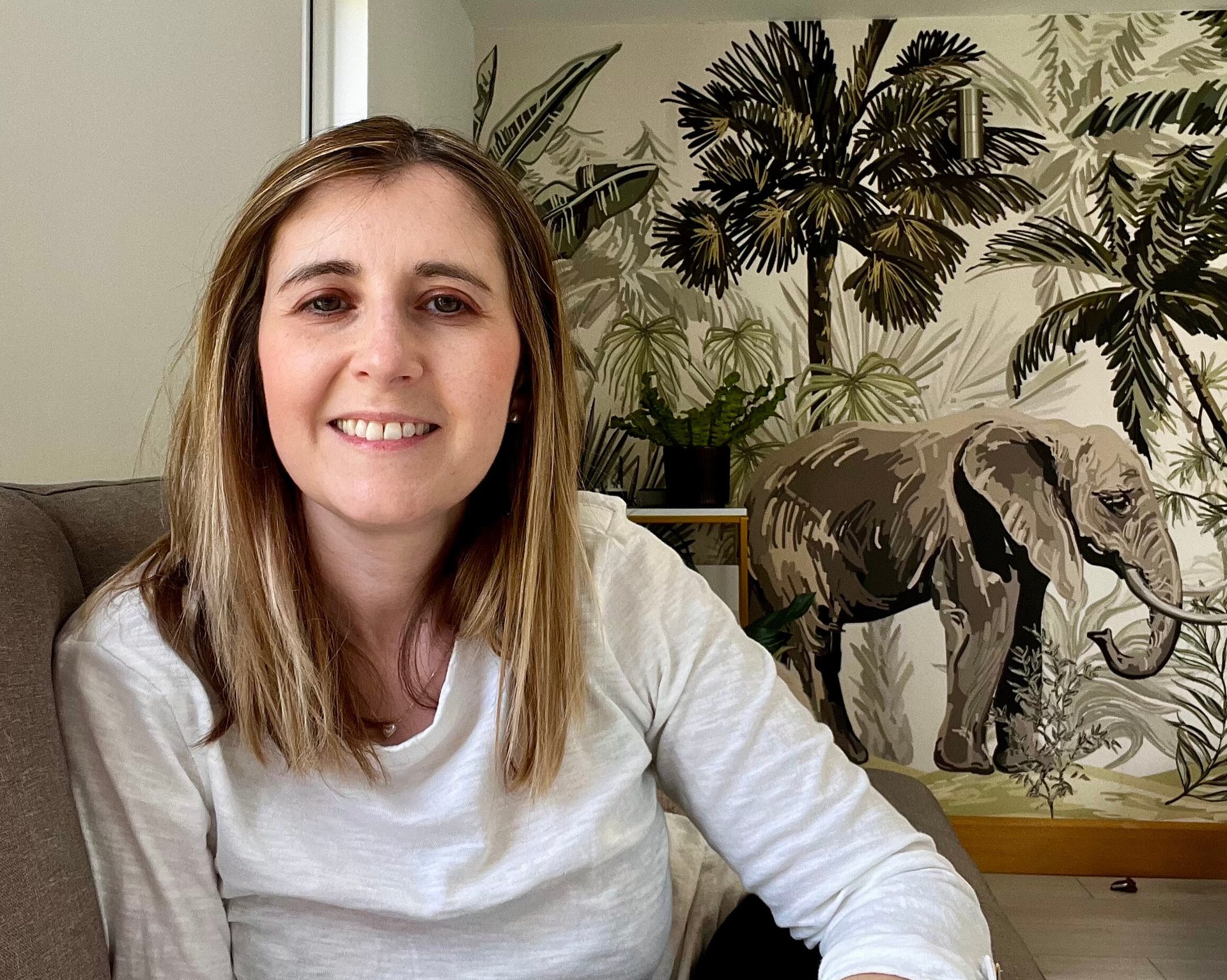 Marina Love, hypnotherapist near Aylesbury, sitting on the sofa in her therapy room.